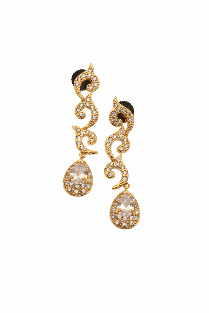 Pair of gold earrings with clear gemstones on a beige background