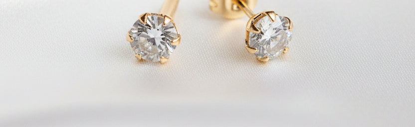 Gold stud earrings with clear gemstones on a black background